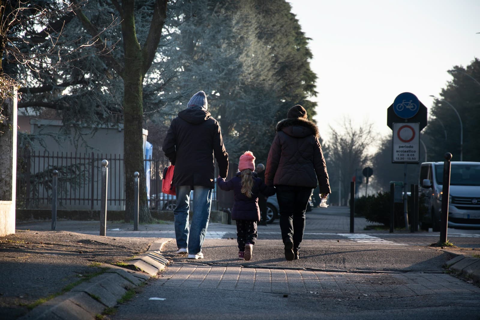 Des parents et un enfant marchent main dans la main dans une rue en hiver.