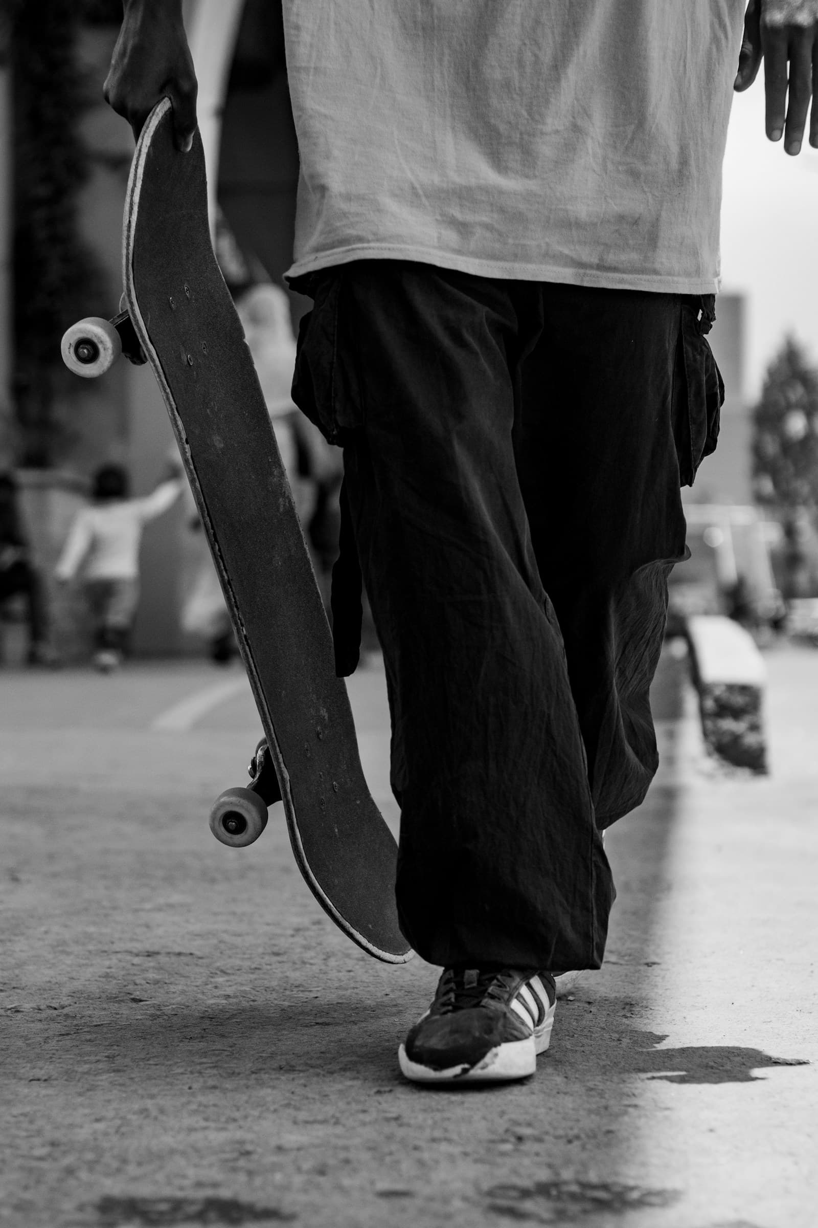 Un adolescent marche en portant son skateboard.