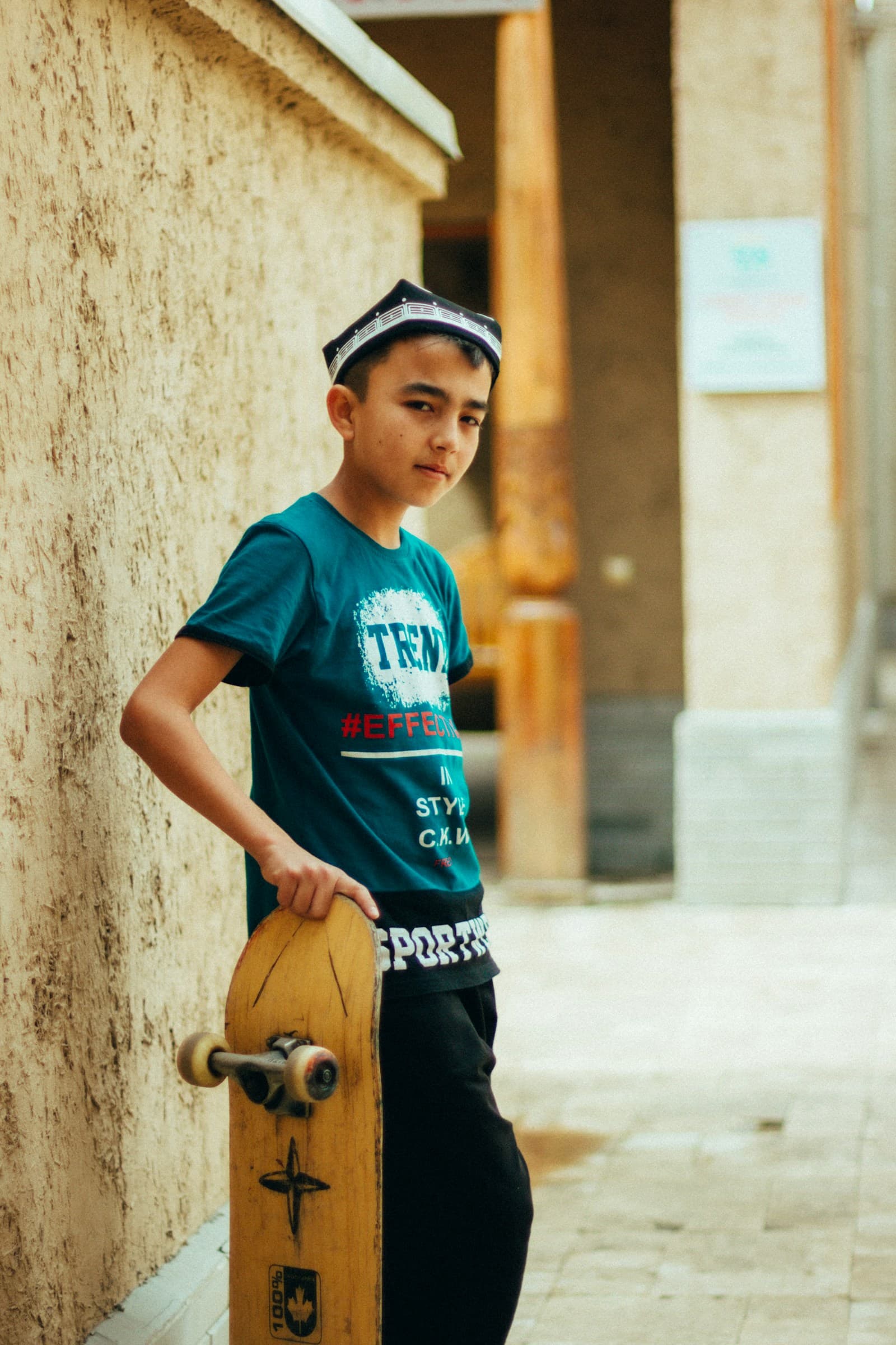 Un adolescent tient son skateboard à la main.