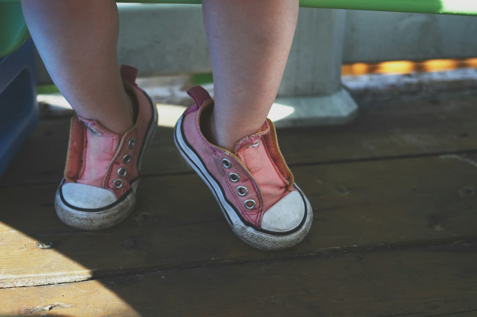 Les pieds d'un tout-petit chaussé de baskets basses noires et blanches.