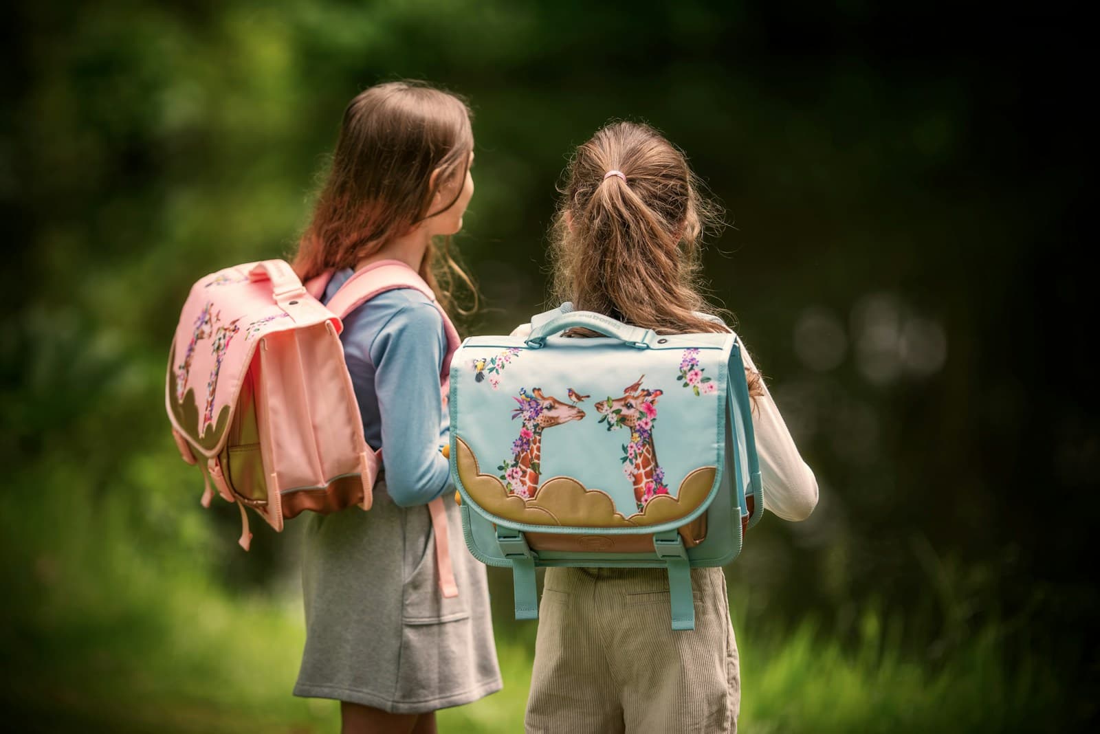 Deux filles debout avec leur sac à dos, au bord de l'eau.