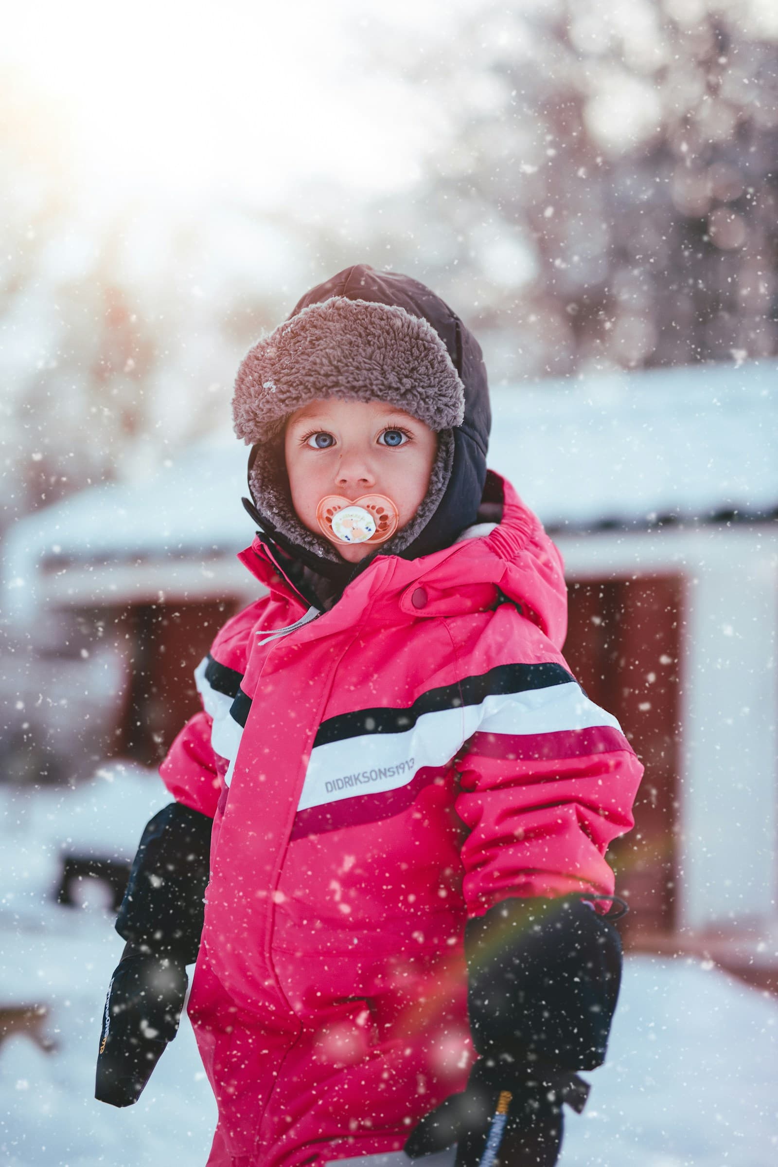 Un enfant en veste zippée rose et bonnet noir, vu de près.