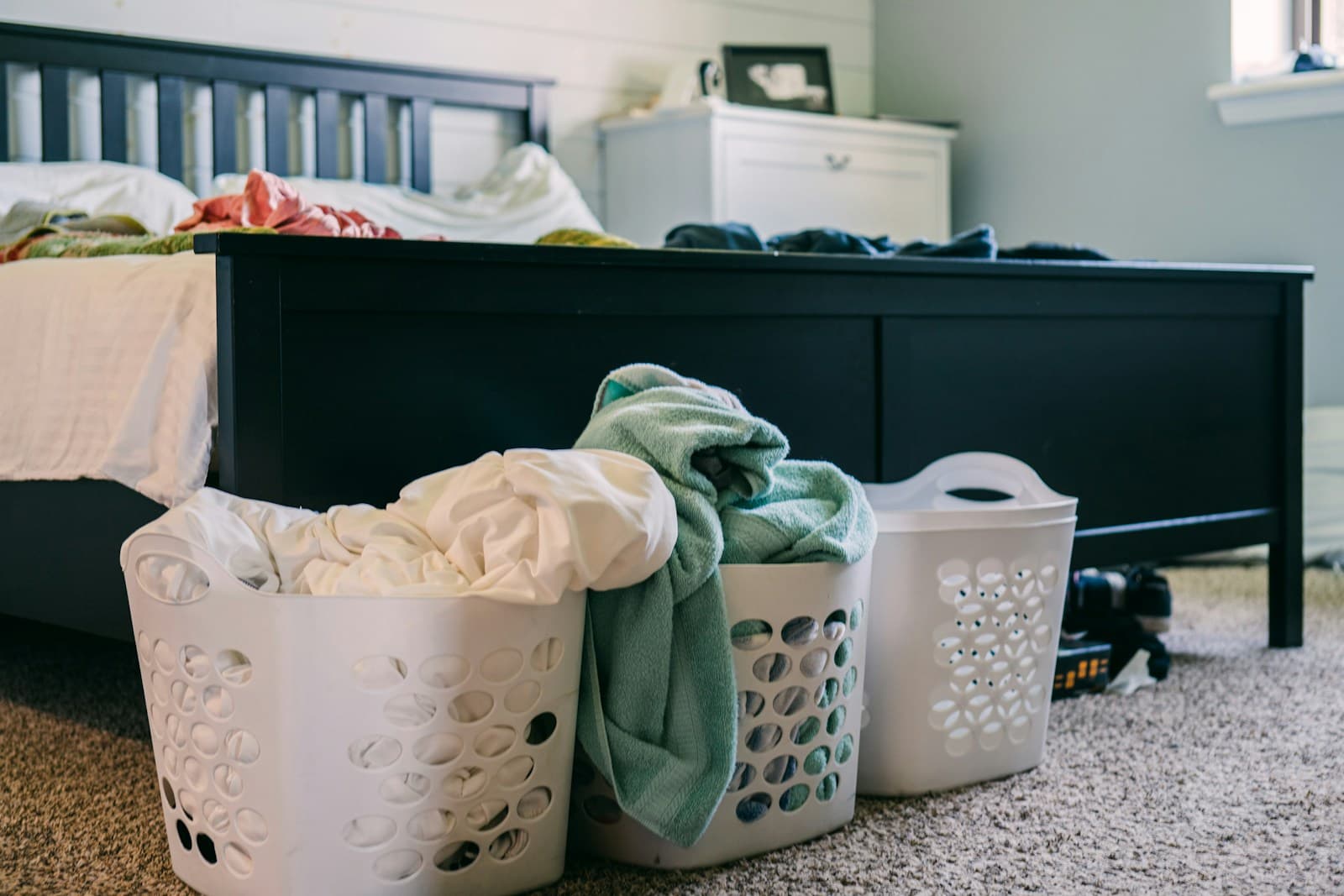 Trois paniers à linge posés au sol dans une chambre.