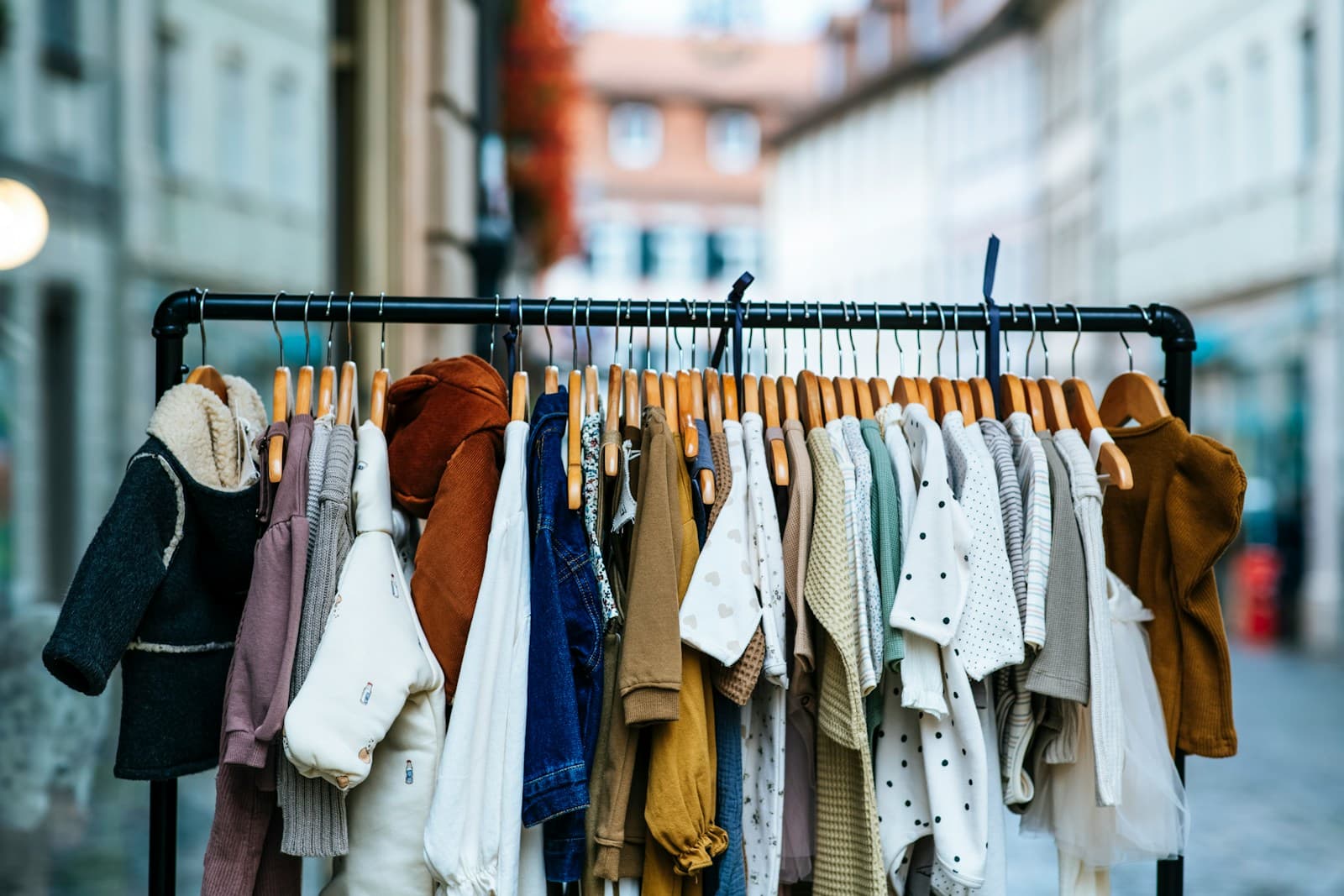Des vêtements suspendus à des cintres, alignés sur une tringle.